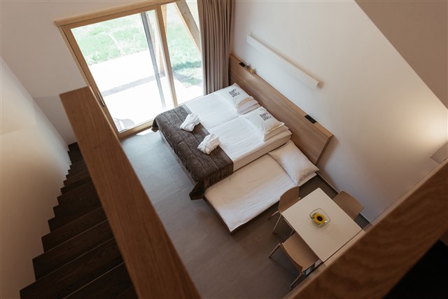 Bungalovy PREKMURSKA VAS AJDA - obývací místnost v přízemí (manželská postel + možnost přistýlky), jednolůžková postel v podkroví - typ Bungalov 3(+1) Superior